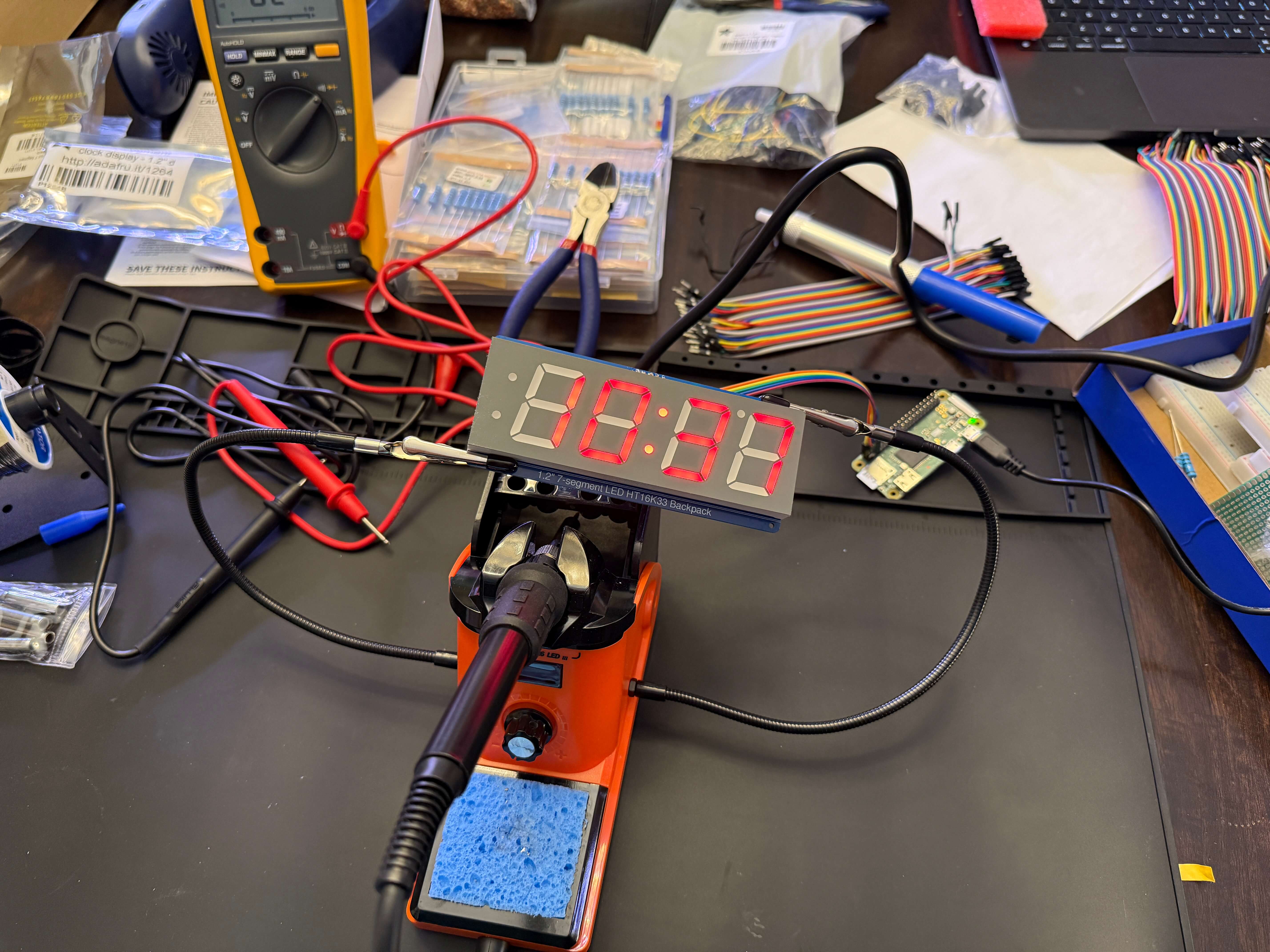 Photograph of a messy work bench with soldering iron, with an Adafruit display (apparently) successfully soldered and operational.