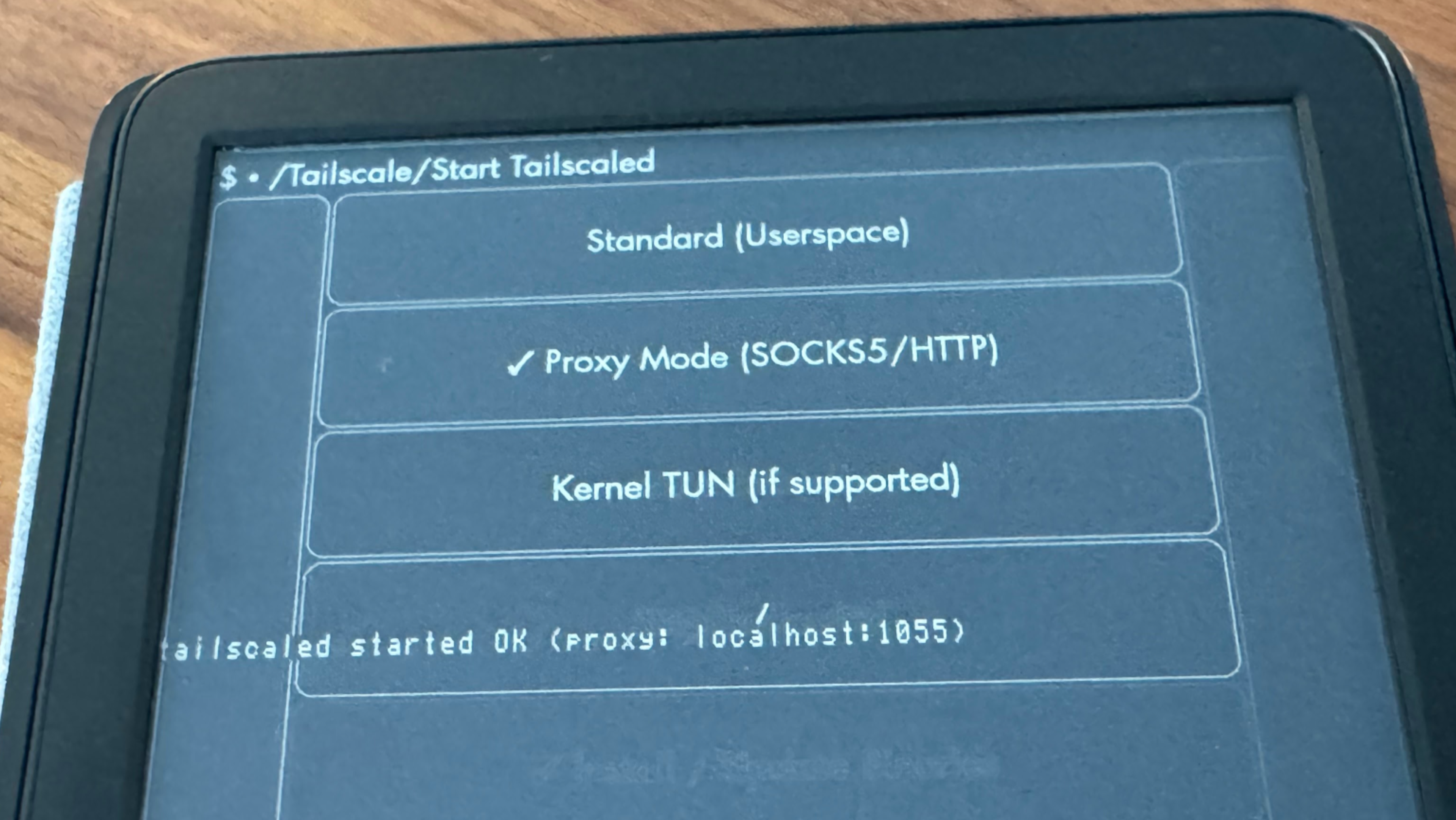 An Amazon Kindle, open to the Tailscale KUAL plug-in, showing three modes: "Standard (Userspace)," "Proxy Mode (SOCKS5/HTTP)," and "Kernel TUN (if supported)". Proxy mode is selected; inlaid text on the screen shows "Tailscaled started OK (proxy: localhost:1055)"