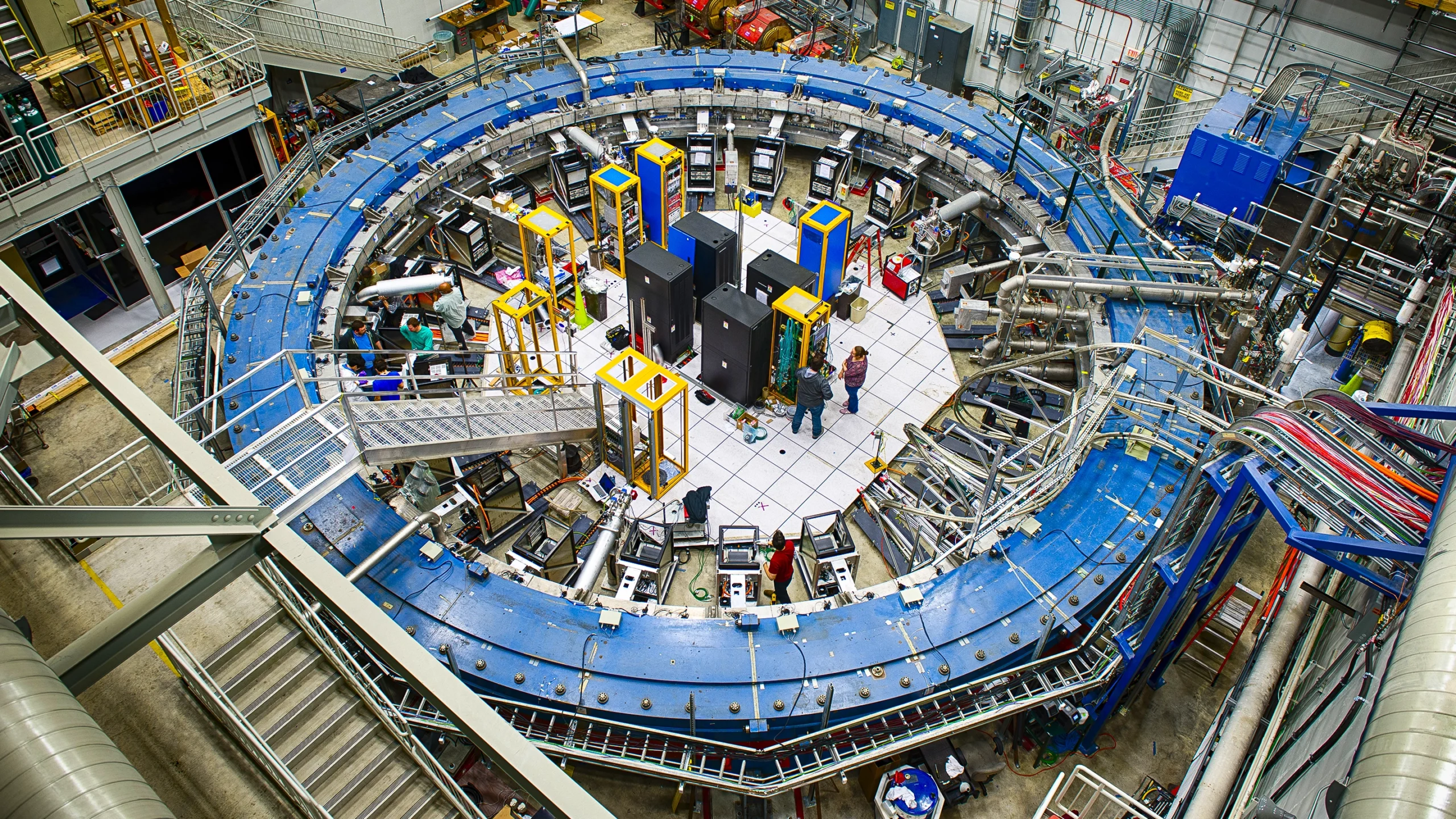 A blue magnetic ring nearly fills a warehouse-sized laboratory.