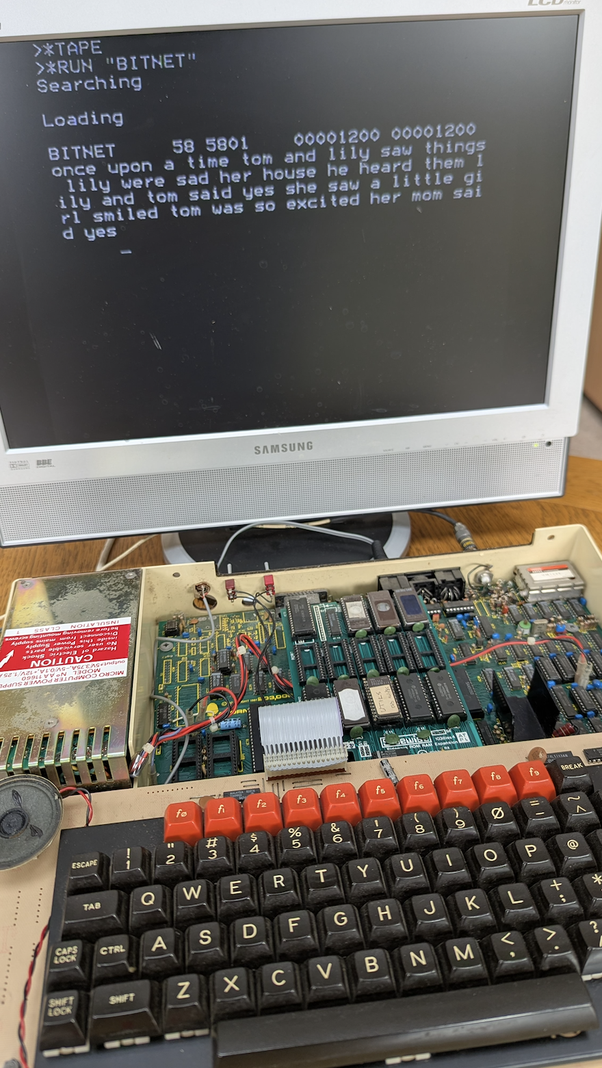 A BBC Micro displaying text generated by the BitNet language model, with its circuit board exposed