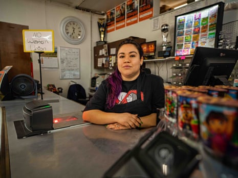A woman behind a counter with a sign that reads, 'No Western Union' in a grocery store