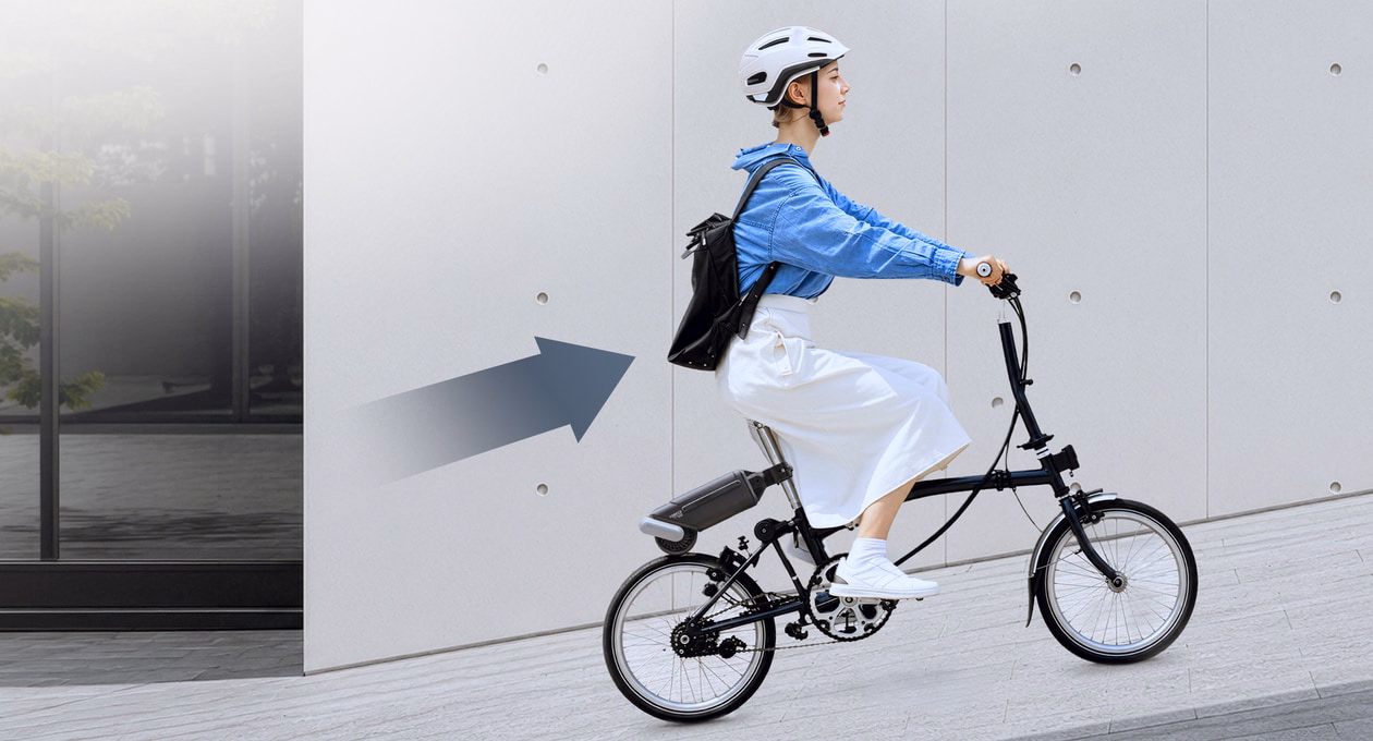 Photo of a girl riding a bike up a slope with the help of the bike booster.
