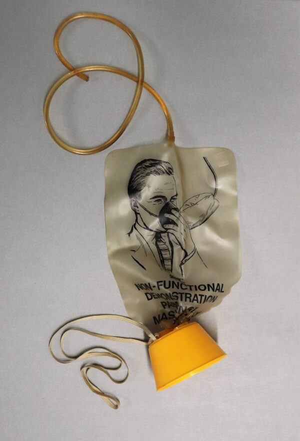 Aircraft passenger oxygen mask; Aircraft removed, drop down passenger mask with air bag and yellow plastic mouth and nose cover, oxygen tube has been cut; Demonstration model used by flight attendant crew for passenger instruction