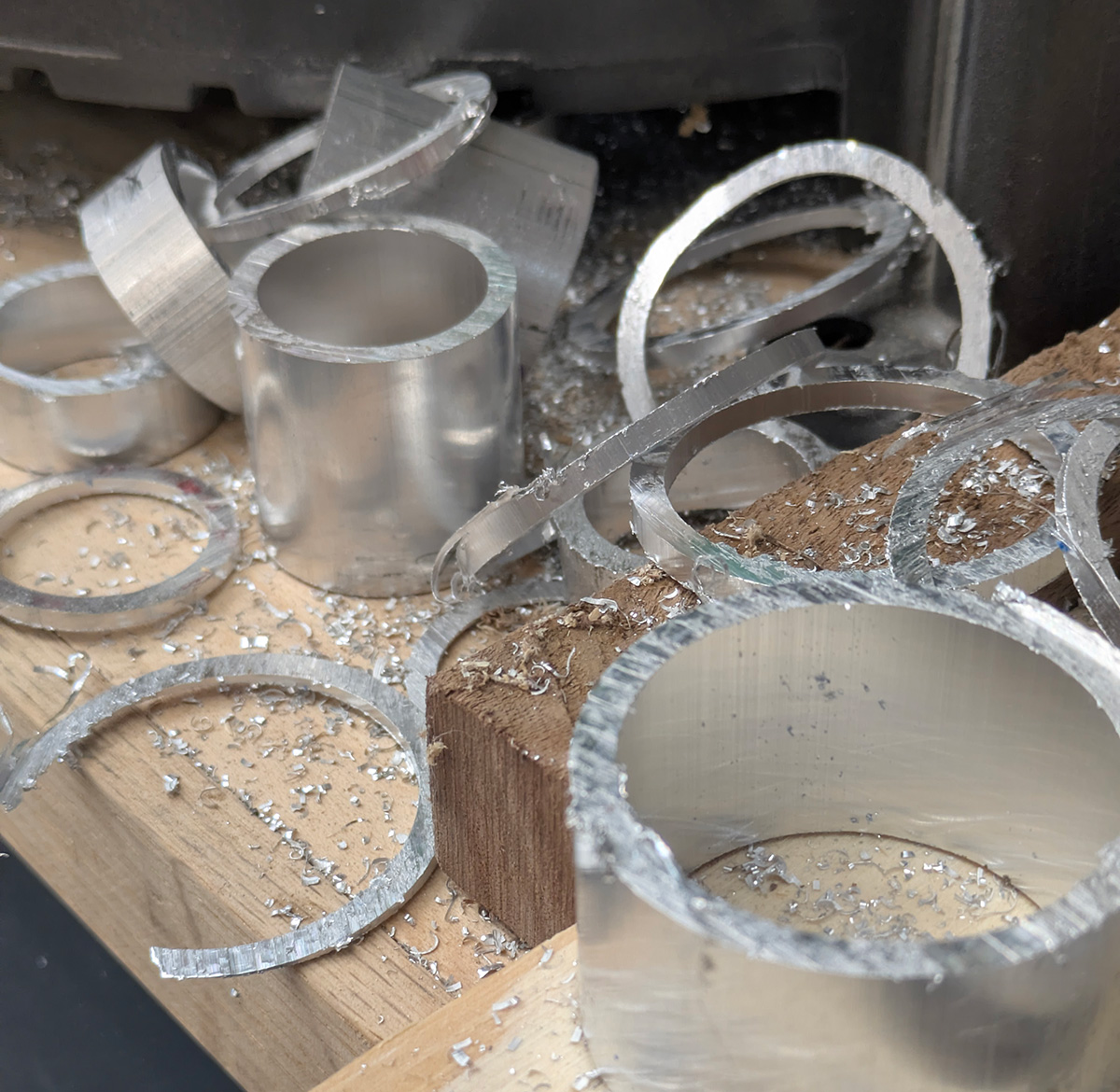 Aluminum pipe pieces and chips are seen on a bench.