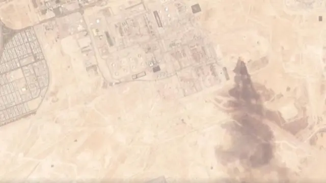 A smoke plume rising over an oil refinery