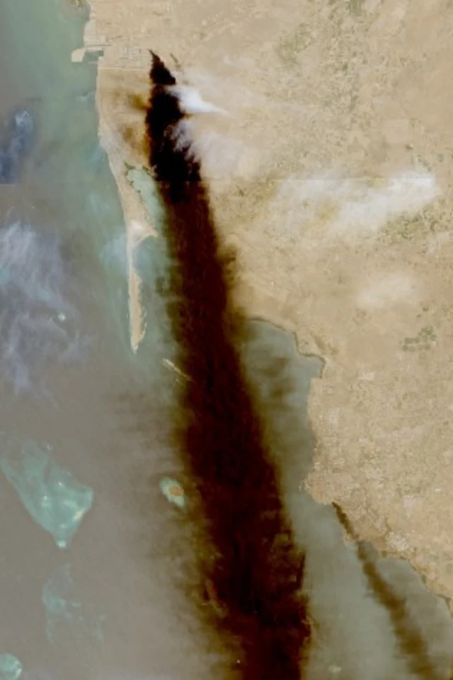 A smoke plume rising over the sea from an oil refinery