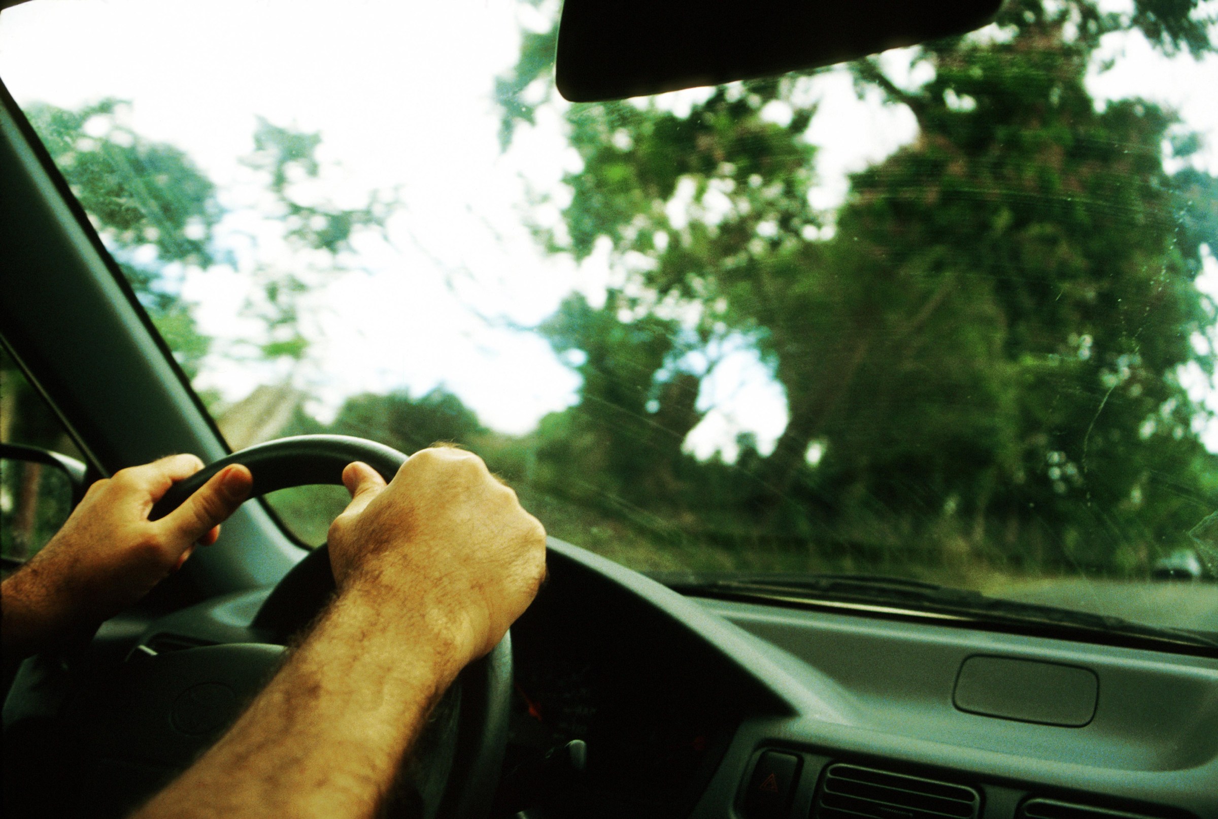 Close Up Of ManS Hands On The Steering Wheel Of A Car.