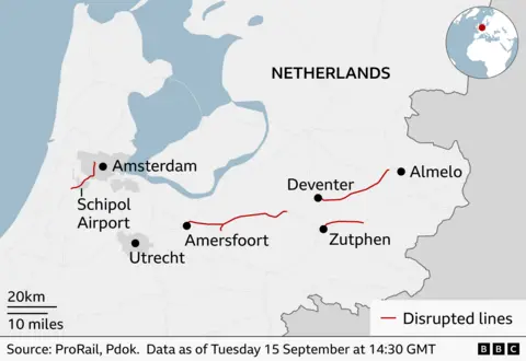 Map of the Netherlands showing rail disruptions on 15 September at 14:30 GMT. Red lines mark disrupted railway sections near Schiphol Airport and between Amersfoort and Deventer, Deventer and Almelo, and around Zutphen. Major locations labeled include Amsterdam, Schiphol Airport, Utrecht, Amersfoort, Deventer, Zutphen, and Almelo. An inset map highlights the Netherlands' location in Europe. A legend indicates that red lines represent disrupted rail lines.