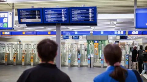 EPA Two people are seen from behind looking up at an information board at Zwolle station in Zwolle, Netherlands, where trains are facing significant disruption